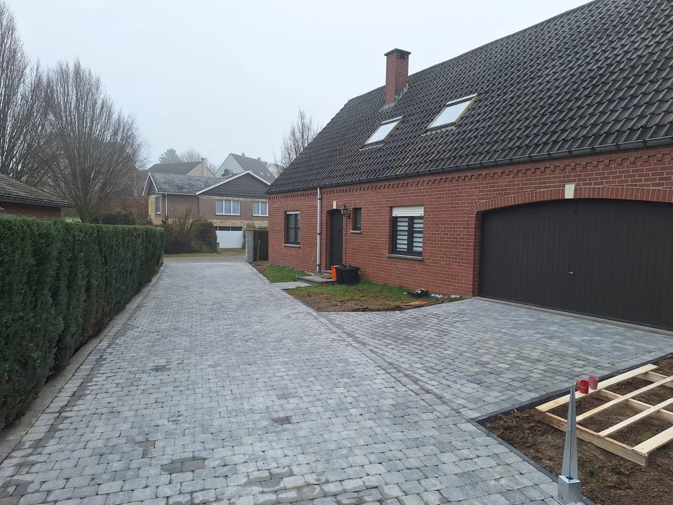 Large cour pavée devant une maison en briques et son garage