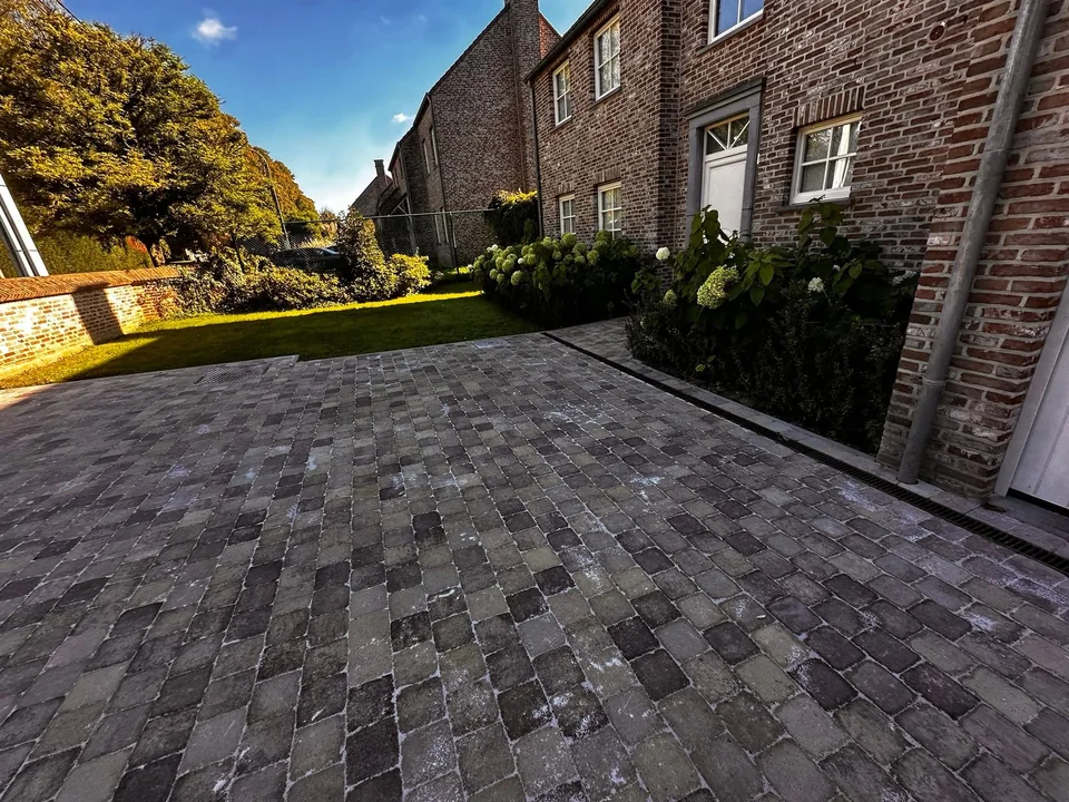 Terrasse pavée devant une maison en briques, ouverte sur le jardin
