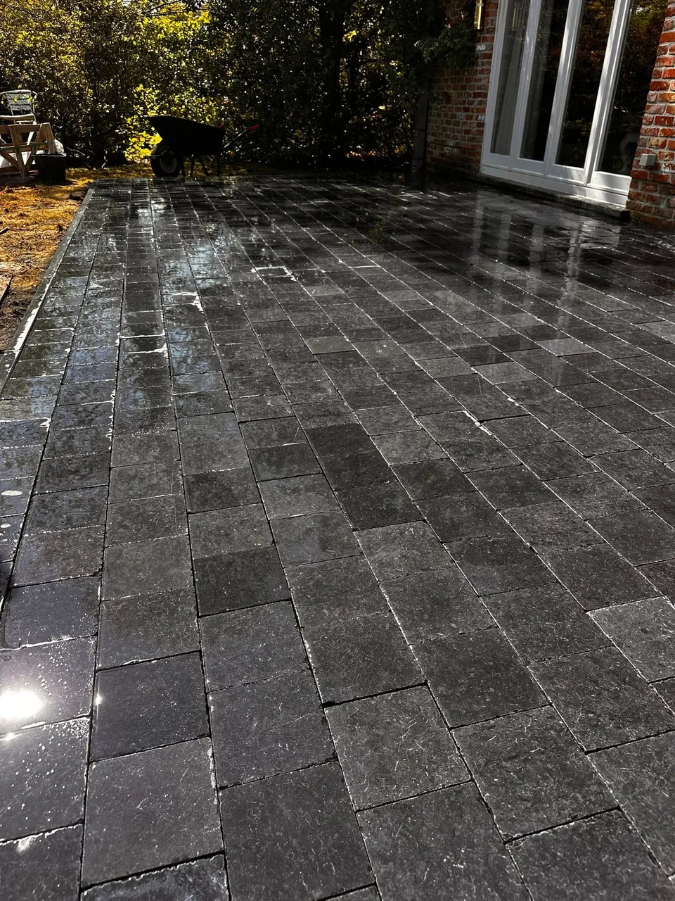 Terrasse en pavés gris devant les baies vitrées d’une maison